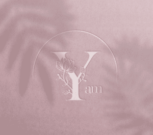 Logo sophistiqué en relief sur fond rose, représentant une lettre y stylisée avec des éléments floraux, évoquant élégance et nature.