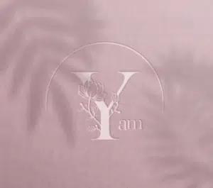 Logo sophistiqué en relief sur fond rose, représentant une lettre y stylisée avec des éléments floraux, évoquant élégance et nature.